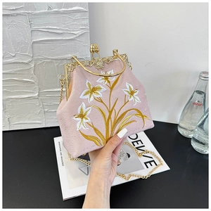 Detail of pink satin bag featuring intricate floral embroidery and gold carved metal frame