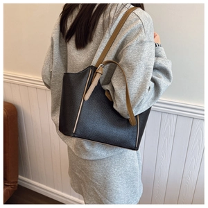 Detailed view of black woven tote bag with brown leather straps worn by a model