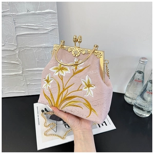 Detail of pink satin bag featuring white lily embroidery and gold-tone metal frame clasp