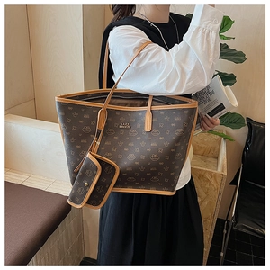 Detail of large tote bag with cat pattern monogram and gold brand logo on high-quality leather