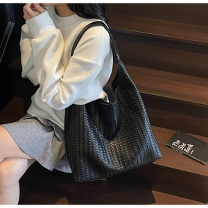 Close-up of black woven leather hobo tote bag with a soft texture and braided handle
