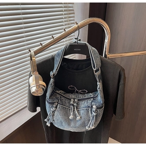 Detail of blue denim crescent bag with multi-zipper pockets and thick rope pullers