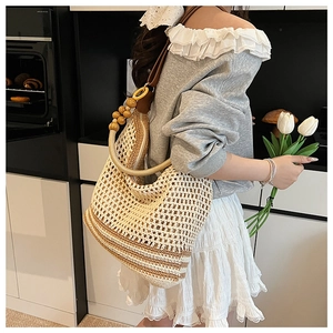 Détail du sac tissé avec perles en bois et poignée ronde aux rayures neutres