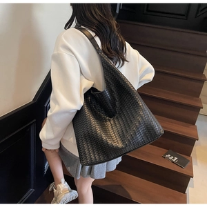 Detail view of a black woven leather tote bag featuring a classic Intrecciato pattern