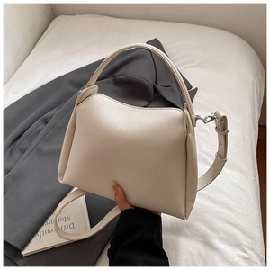 Detail of minimalist creamy white handbag with fine pebble texture and elegant handle