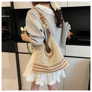Detail of woven mesh shoulder bag featuring a unique wooden bead and ring strap design