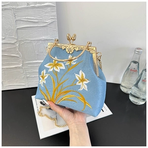 Detail of light blue silk party bag with floral embroidery and vintage gold metal frame