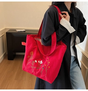 Close-up of vibrant red tote bag with detailed colorful floral embroidery and wide strap
