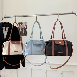 Three nylon travel bags in beige, blue, and black with leather handles and straps