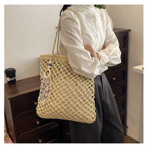 Close-up of beige hollow woven tote bag featuring beaded fringe and fabric lining