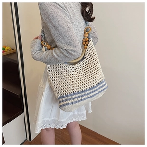 Detail of hand-woven straw beach bag with blue stripes and wooden beaded shoulder strap