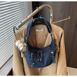 Close-up of blue denim hobo bag featuring stylish long fringe zippers on a display rack