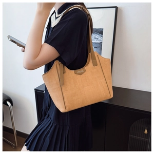 Detail of caramel tote bag with woven texture, leather straps, and metal JINGPIN logo plaque