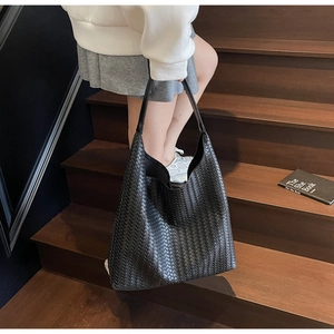 Detail of black woven leather tote bag showing intricate grid texture and hobo style