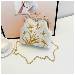 Detail of floral embroidery on cream canvas bag with vintage gold metal frame and clasp