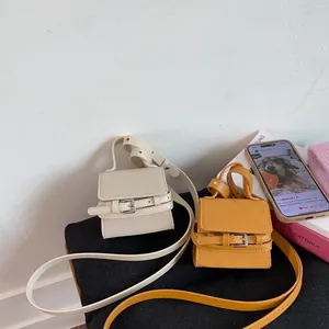 Detailed shot of mini crossbody bags in beige and yellow with retro belt buckle hardware