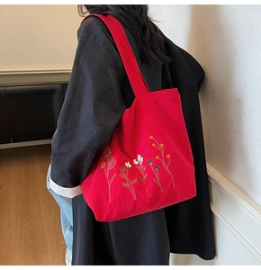 Close-up of red canvas tote bag featuring delicate colorful wildflower embroidery details