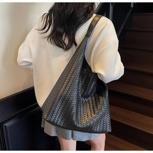 Detail shot of the black woven leather texture on a large capacity hobo shoulder bag
