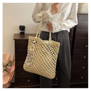 Detail of hollow-out woven tote bag with blue bead tassel and woven handles