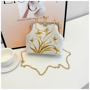 Detail of lily embroidery and vintage gold clasp on a beige canvas chain crossbody bag