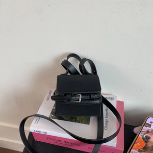 Detailed view of black mini square crossbody bag with metal buckle strap on magazines