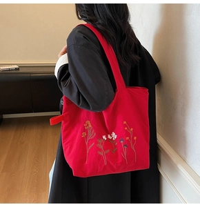 Close-up of red canvas tote bag featuring vibrant wildflower embroidery on a shoulder bag