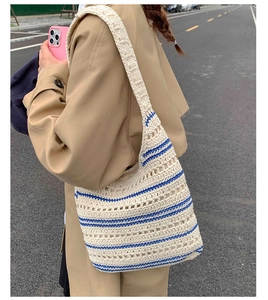 Detailed close-up of woven cotton tote bag with navy stripes worn over the shoulder