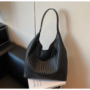 Detailed close-up of a premium black woven leather hobo bag on a minimalist background