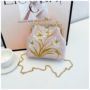 Close-up of vintage pink embroidered floral canvas bag with gold kiss-lock and metal chain