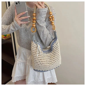 Détail du sac tissé avec poignées en grosses perles de bois et bordure au crochet