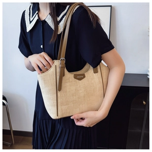 Close-up of woven tote bag with brown leather handles and Jingpin logo brand tag