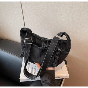Close-up of black denim crossbody bag featuring multiple zipper pockets and rope pullers