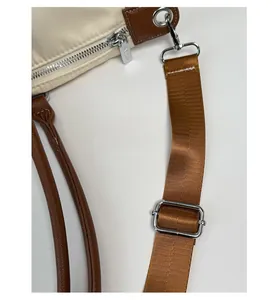 Detail of wide adjustable brown shoulder strap and leather handles on travel bag