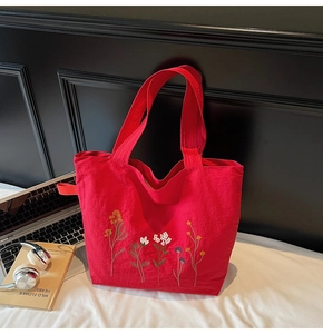 Detail of red canvas tote bag featuring intricate floral embroidery and large capacity