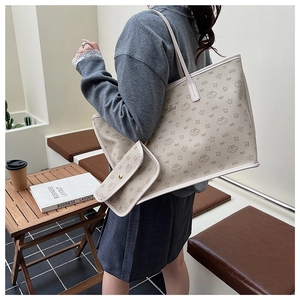 Side view of model carrying a beige patterned tote bag and matching small pouch