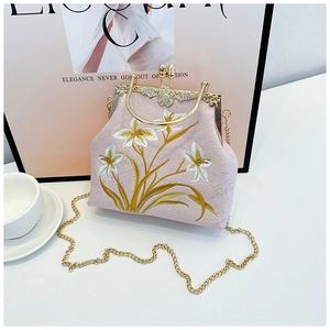 Detail of floral embroidery on pink canvas bag with gold kiss-lock and pearl clasp
