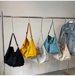 Selection of colorful nylon tote bags in black, yellow, grey, blue and beige hanging on rack