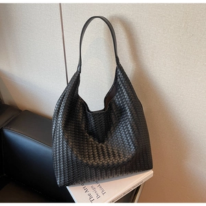 Detailed view of woven black leather texture on a minimalist hobo tote bag