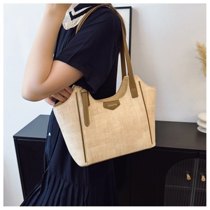 Detail of woven straw tote bag with brown leather straps and vintage Jingpin tag