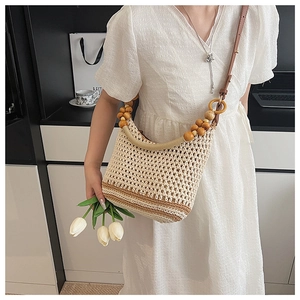 Détail du sac à bandoulière tissé avec sangle en perles de bois et texture en paille