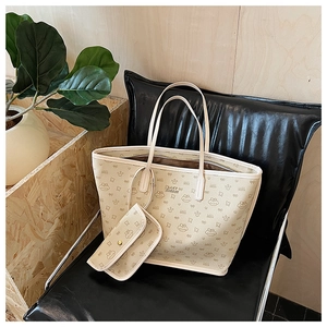 Detail of beige monogram tote bag with cartoon bear print on a black leather chair