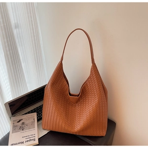 Detailed macro view of brown woven leather texture on a vintage tote shoulder bag