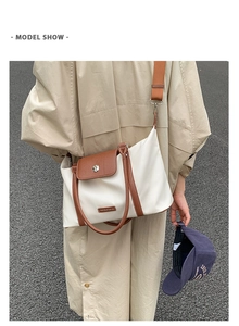 Close-up of white waterproof travel bag with brown leather trim and metal buckle detail