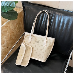 Detail of cream faux leather tote bag set with cute puppy prints and metal logo