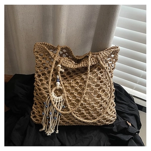Detail of hollow woven straw tote bag featuring blue evil eye bead tassel and wood texture