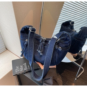 Detailed close-up of dark denim hobo bag featuring multiple zip pockets and metal buckles