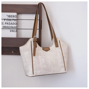 Detail of a chic tote bag featuring beige linen texture and brown leather trim details