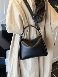 Classic black litchi pattern leather handbag shown from a side view on a model