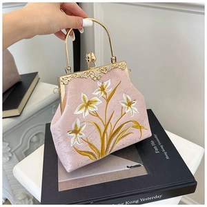 Close-up of pink satin embroidery bag with floral patterns and gold metal handle