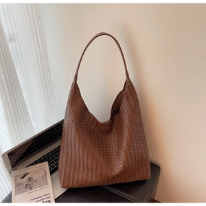 Detail of a brown woven leather hobo tote bag on a white desk for work commute